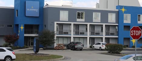 A modern building with a blue facade, a stop sign, and several parked cars.