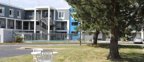 A two-story building with balconies and a tree in the foreground.