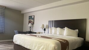 A hotel room with a large bed, two bedside tables, a desk, and a chair. - Quality Inn Rhinelander (Rhinelander)