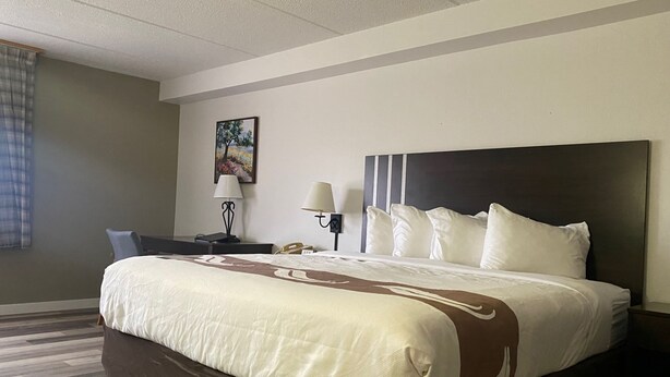 A hotel room with a large bed, two bedside tables, a desk, and a chair. - Quality Inn Rhinelander (Rhinelander)