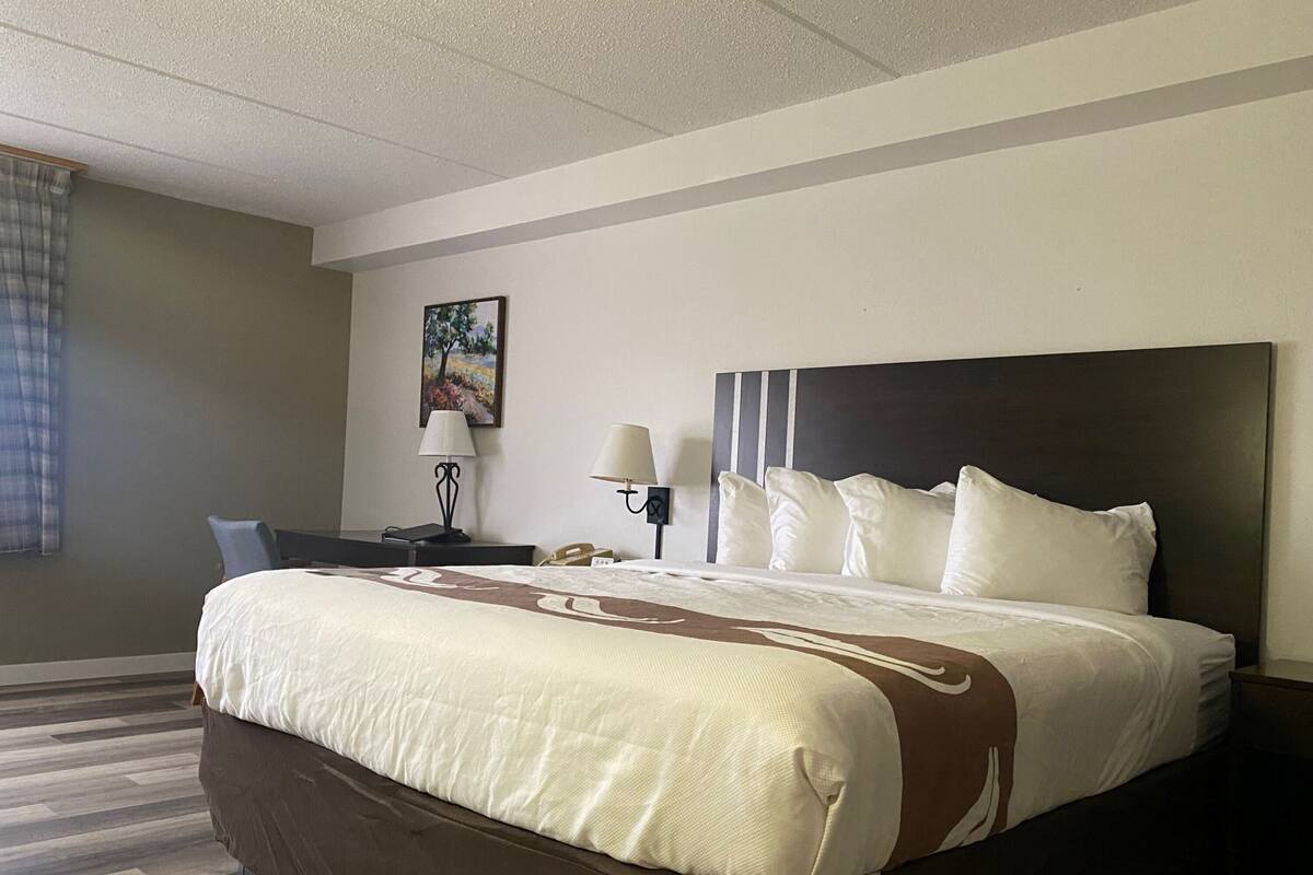 A hotel room with a large bed, two bedside tables, a desk, and a chair.