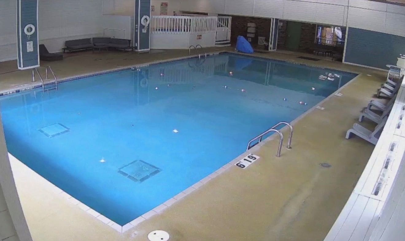 An indoor swimming pool with clear water, marked lanes, and a lifeguard chair.