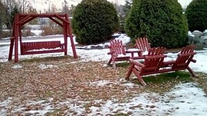 A wooden swing set and Adirondack chairs in a snowy outdoor area. - Quality Inn Rhinelander (Rhinelander)