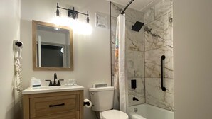 A bathroom with a toilet, sink, mirror, and shower. - Quality Inn Rhinelander (Rhinelander)