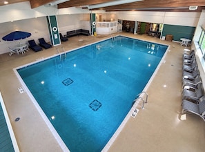 An indoor swimming pool with lounge chairs, a sunbed, and a lifeguard stand. - Quality Inn Rhinelander (Rhinelander)