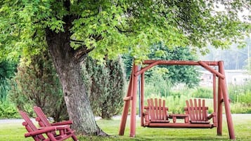 A wooden swing set under a large tree in a park.