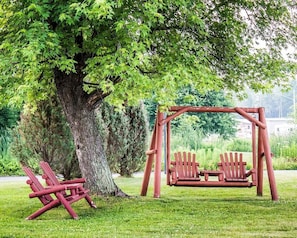 A wooden swing set under a large tree in a park. - Quality Inn Rhinelander (Rhinelander)