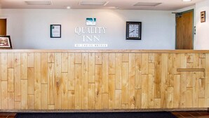A reception desk with a wooden panel design, a clock, and framed certificates on the wall. - Quality Inn Rhinelander (Rhinelander)