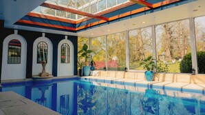 A modern indoor pool with a glass ceiling, large windows, and a view of the garden. - The Spa Hotel (Royal Tunbridge Wells)