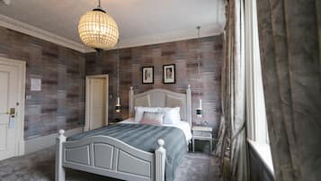 Ein Schlafzimmer mit einem großen Bett, einem Nachttisch, einer Lampe und einem Fenster mit Vorhängen.
