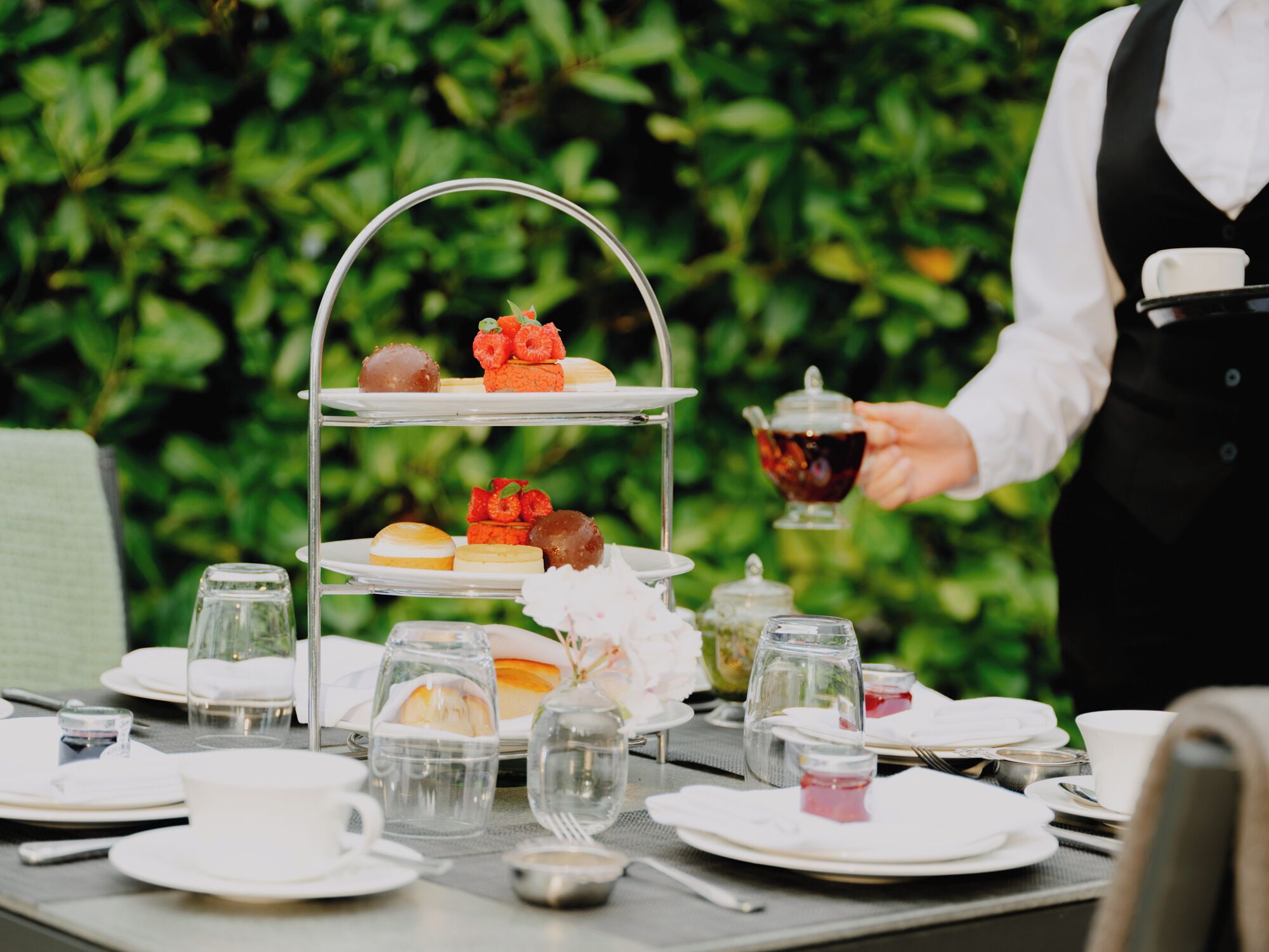Un présentoir à trois niveaux pour le service du thé, avec des pâtisseries et une théière.