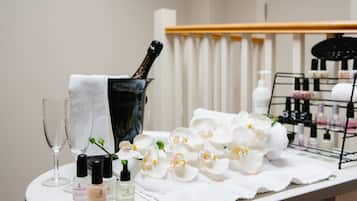 A table with a bottle of champagne, two glasses, and a tray of white flowers.