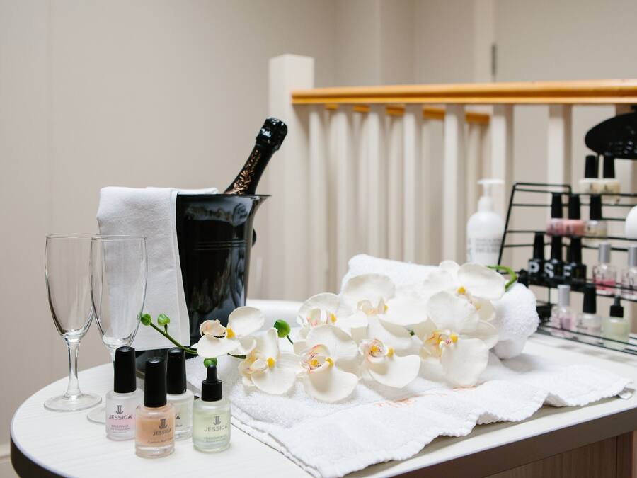 A table with a bottle of champagne, two glasses, and a tray of white flowers.