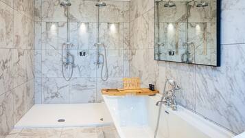A modern bathroom with a walk-in shower, a bathtub, and a large mirror.