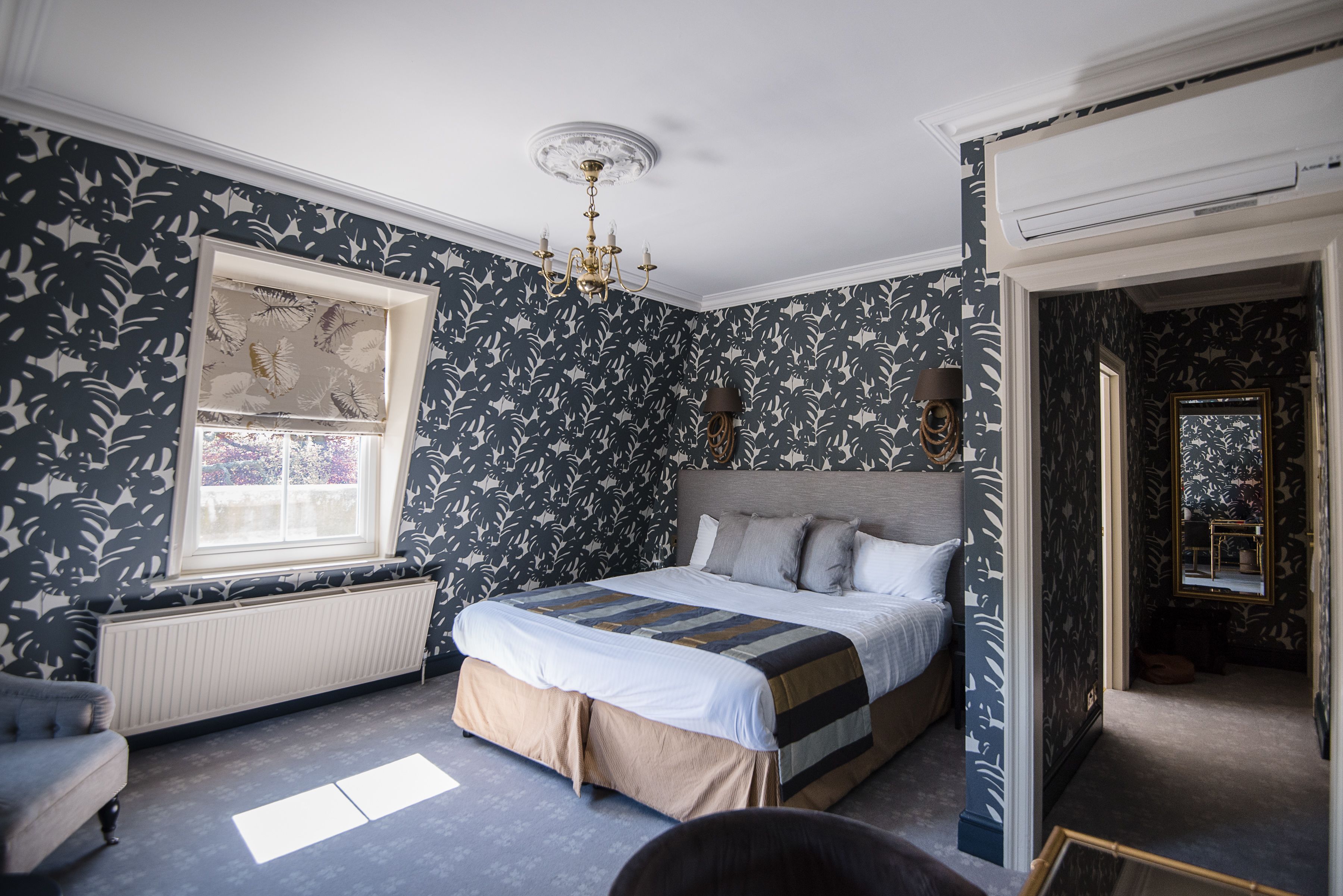 Une chambre à coucher comprenant un lit, un radiateur, une fenêtre et une porte donnant sur une autre pièce.