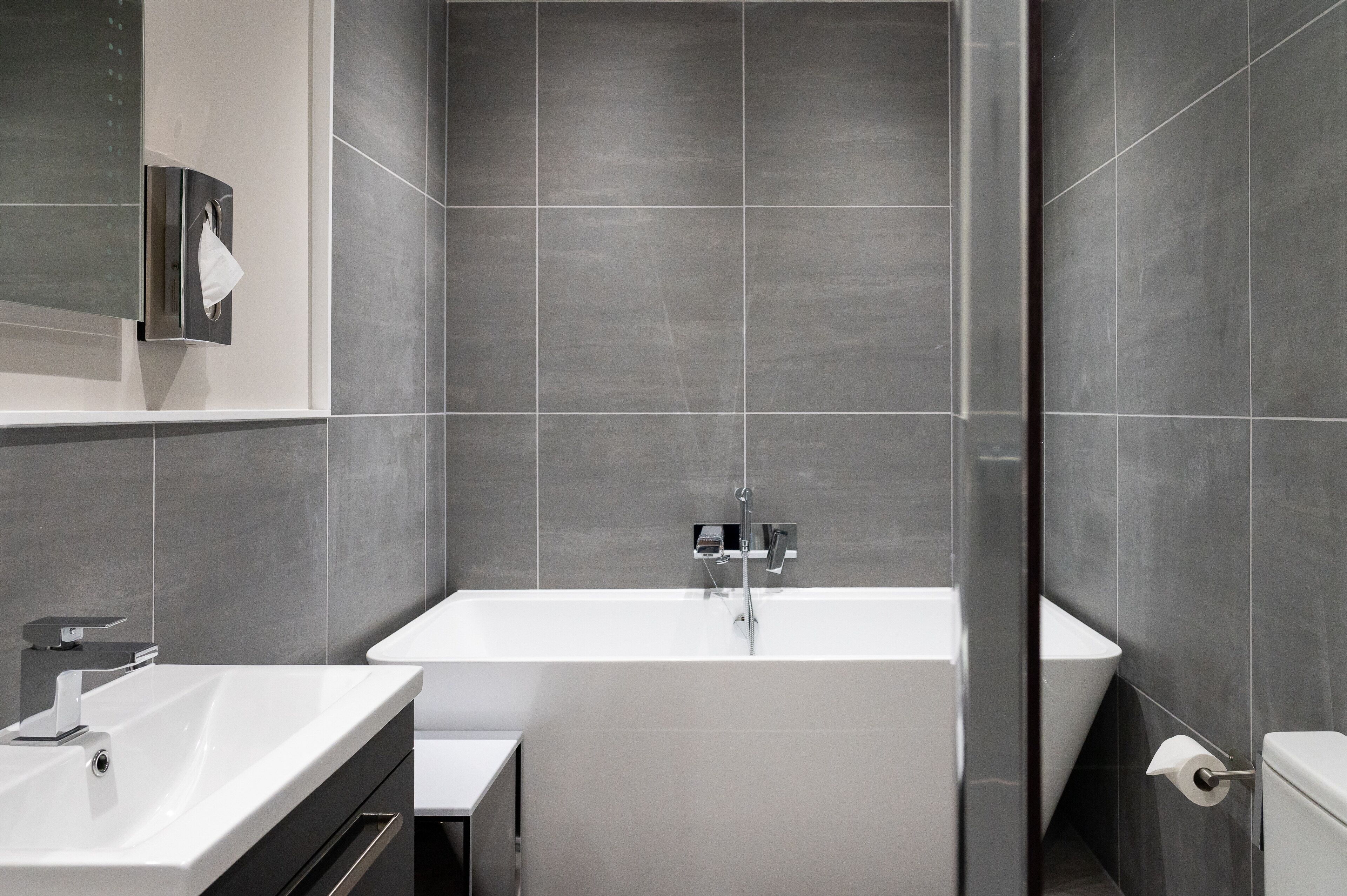 Een moderne badkamer met een groot bad, een wastafel en een toilet.