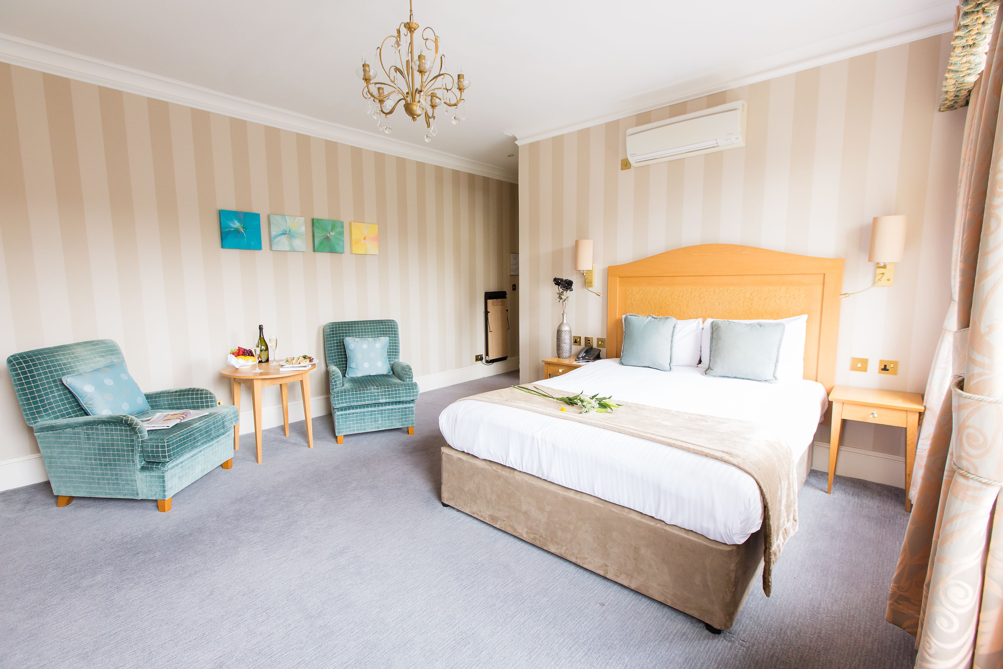 Ein Hotelzimmer mit einem großen Bett, zwei Sesseln, einem kleinen Tisch und einer Kristallleuchtre.