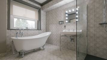 A bathroom with a freestanding bathtub, a sink, and a mirror with lights.