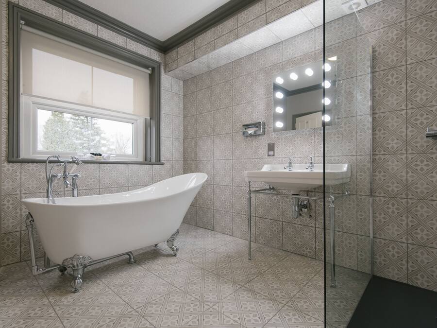 A bathroom with a freestanding bathtub, a sink, and a mirror with lights.
