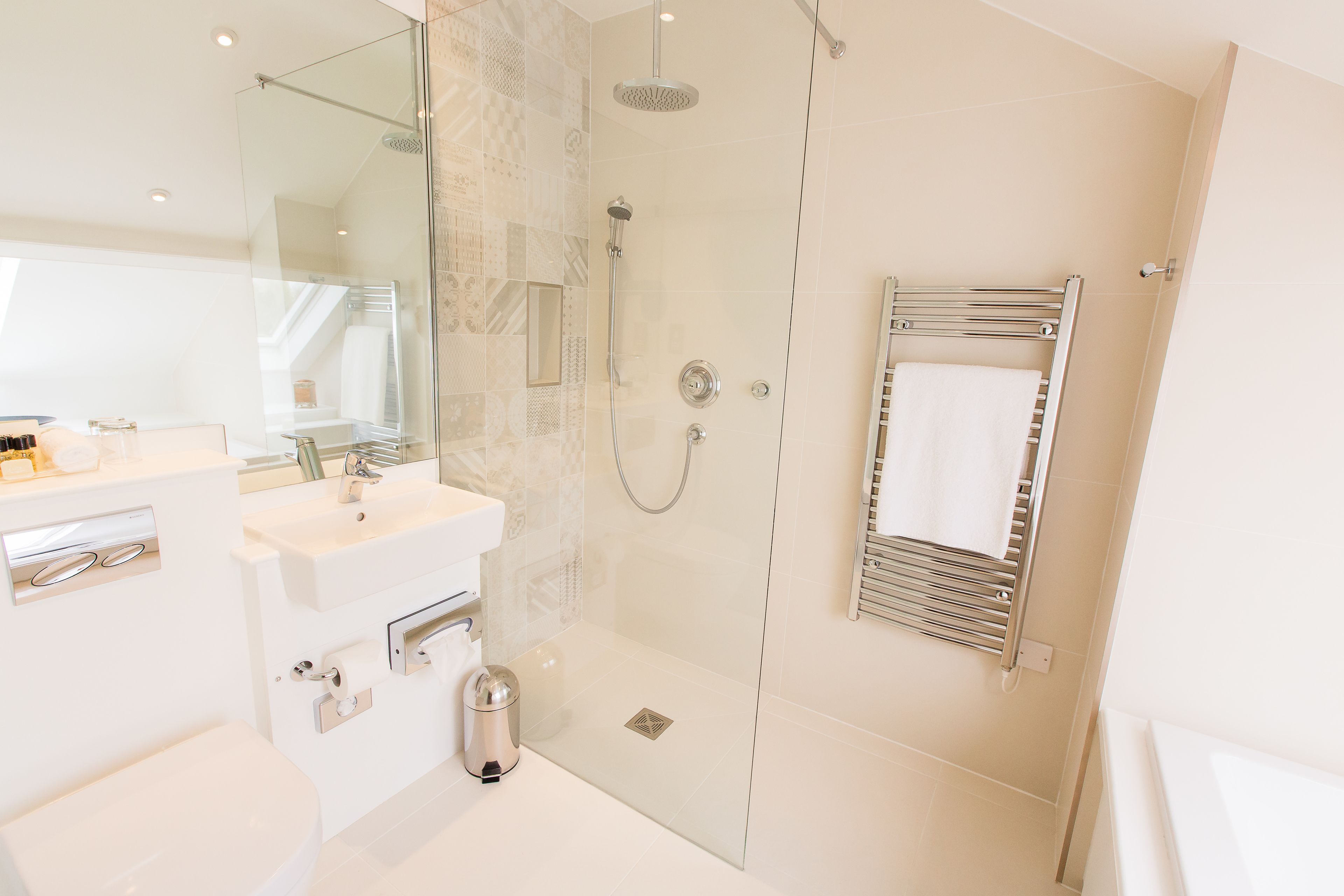 A modern bathroom with a glass-enclosed shower, a white sink, and a towel rack.