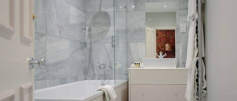 A modern bathroom with a bathtub, shower, and vanity.