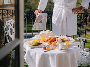 A breakfast table with a newspaper, fruits, pastries, and beverages, set on a balcony with a railing. - The Spa Hotel (Royal Tunbridge Wells)