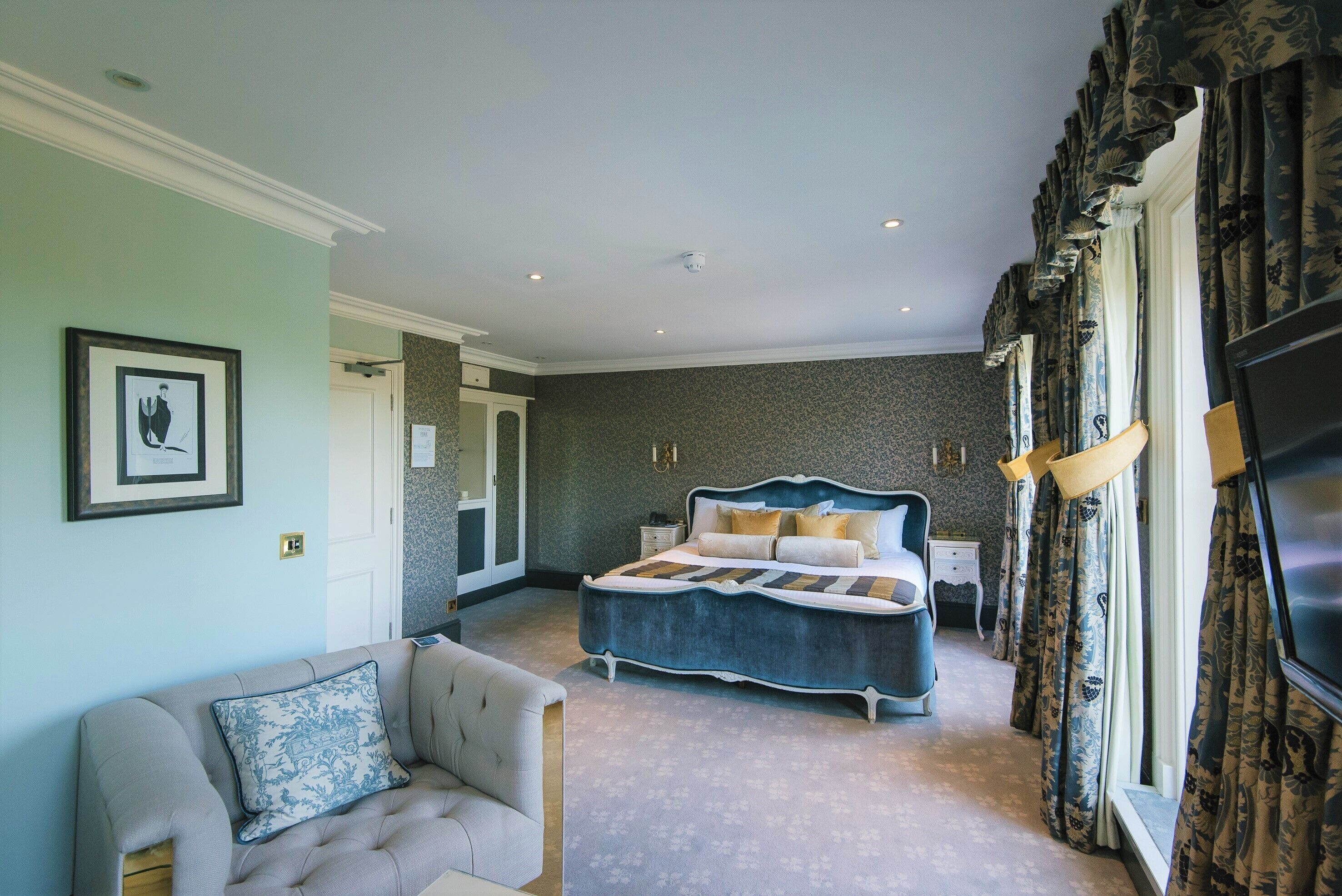 A bedroom with a large bed, a sofa, and a television.