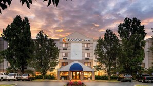 Un hotel Comfort Inn con entrada central, zona de estacionamiento y árboles circundantes.