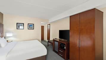 A hotel room with a bed, a desk, a television, and a wardrobe.