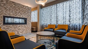 Uma área de estar moderna com parede de pedra, lareira e cortinas estampadas.