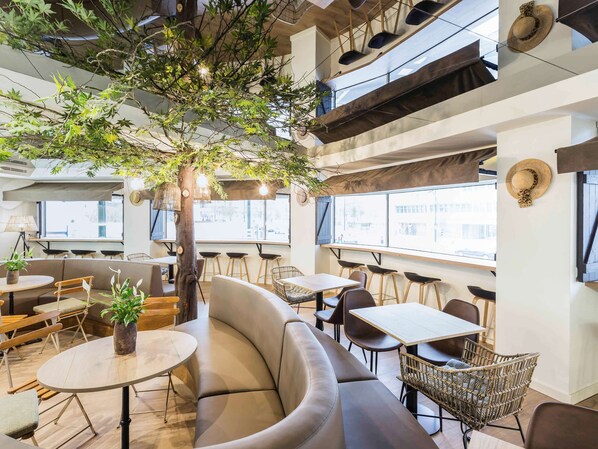 Relax in a spacious seating area with a curved sofa and multiple tables, surrounded by a natural centerpiece and plenty of space to dine or socialize.