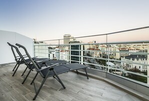 Relax on the balcony with a clear view of the city, featuring a set of lounge chairs and a small table.