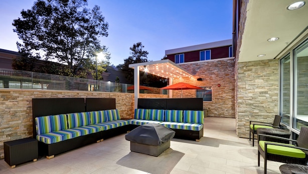 Ein Terrassenbereich mit Ecksofa, überdachter Sitzgruppe und Korbstühlen.