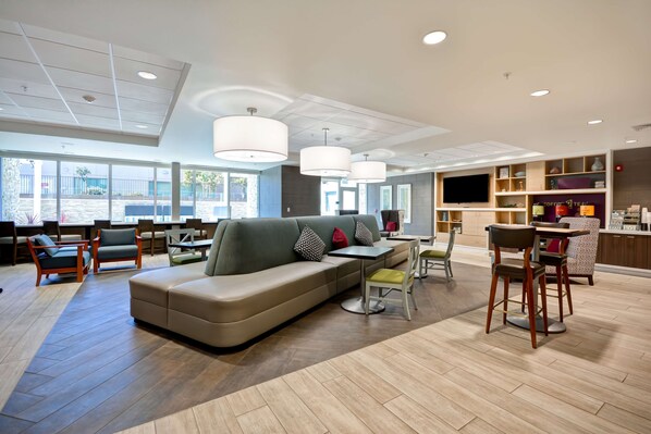 A modern lounge area with a sofa, chairs, a bar, and a television.