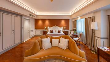 A spacious bedroom with a large bed, a sofa, a nightstand, and a lamp.