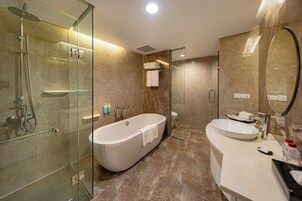 A modern bathroom with a glass-enclosed shower, a freestanding bathtub, and a vanity with a sink and mirror.