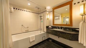 A modern bathroom with a bathtub, a shower, a sink, and a large mirror.