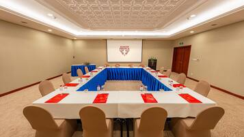 A conference room with a long table, beige chairs, and a projector screen displaying "SAIGON PRINCE".