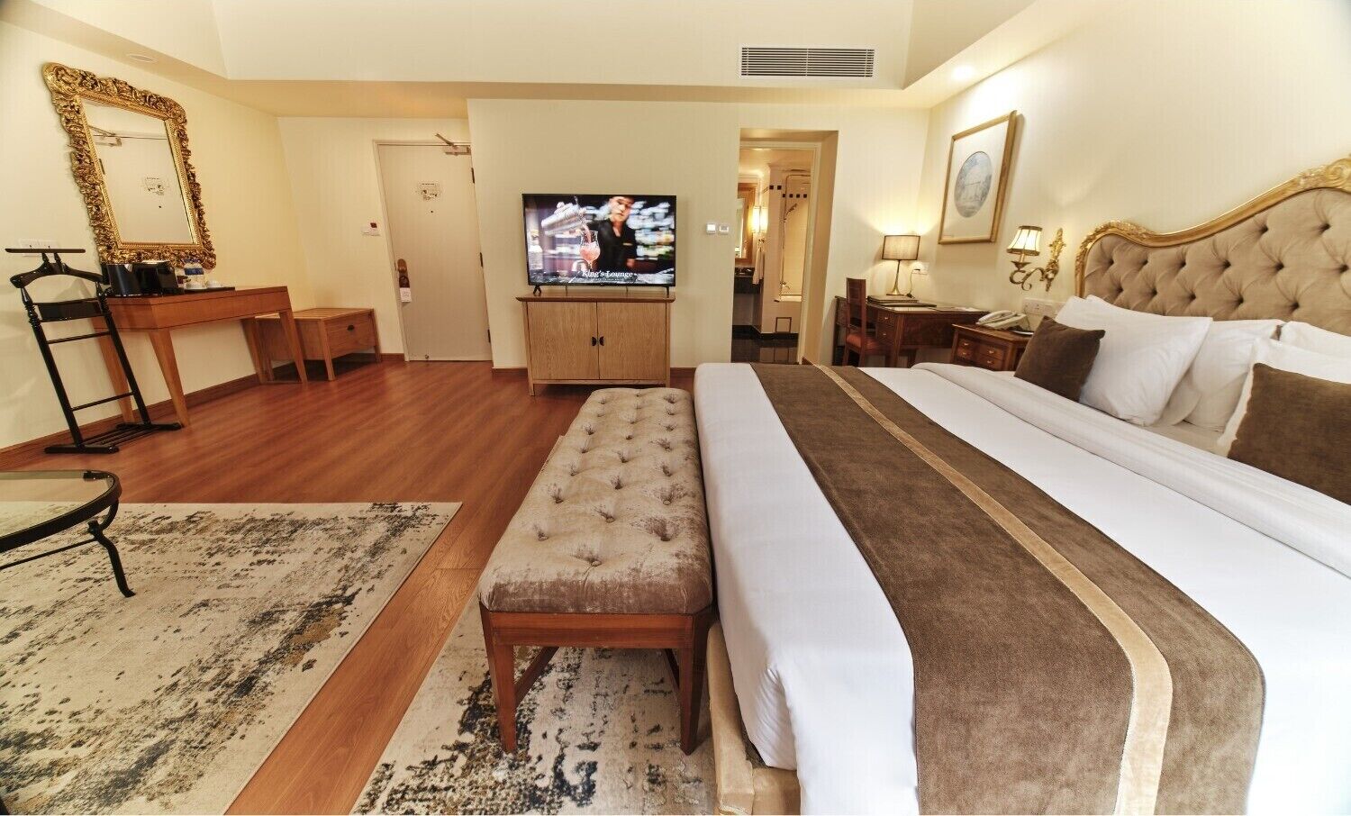 Une chambre d’hôtel avec un grand lit, une télévision, un bureau et un miroir.