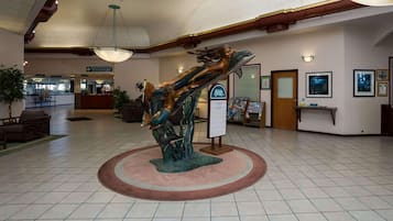 A lobby with a central sculpture, a reception desk, and a sign for a restaurant and lounge.
