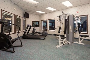 Un gimnasio con cintas de correr, escaladora y máquina de pesas.