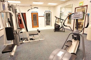 Un gimnasio con diversos equipos de ejercicio, incluyendo una cinta de correr, una elíptica y máquinas de pesas.