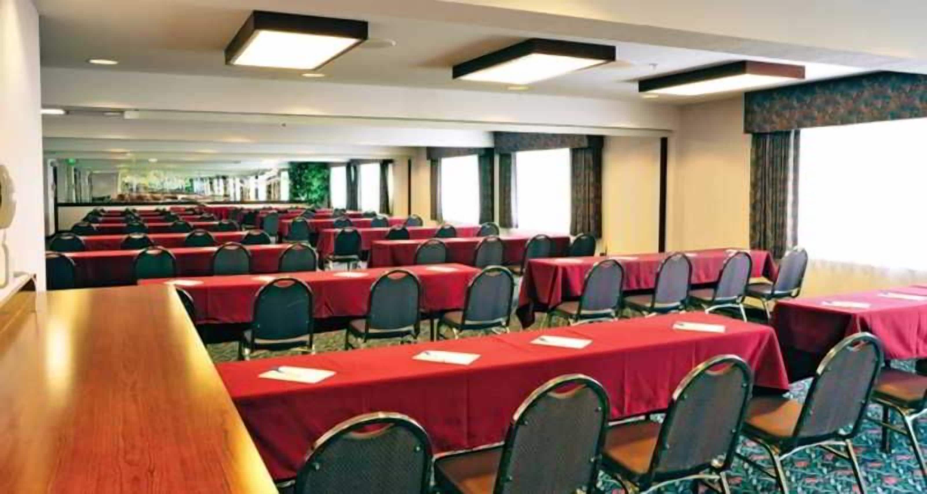 A conference room with multiple tables and chairs, arranged in rows.