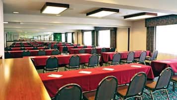 A conference room with multiple tables and chairs, arranged in rows.