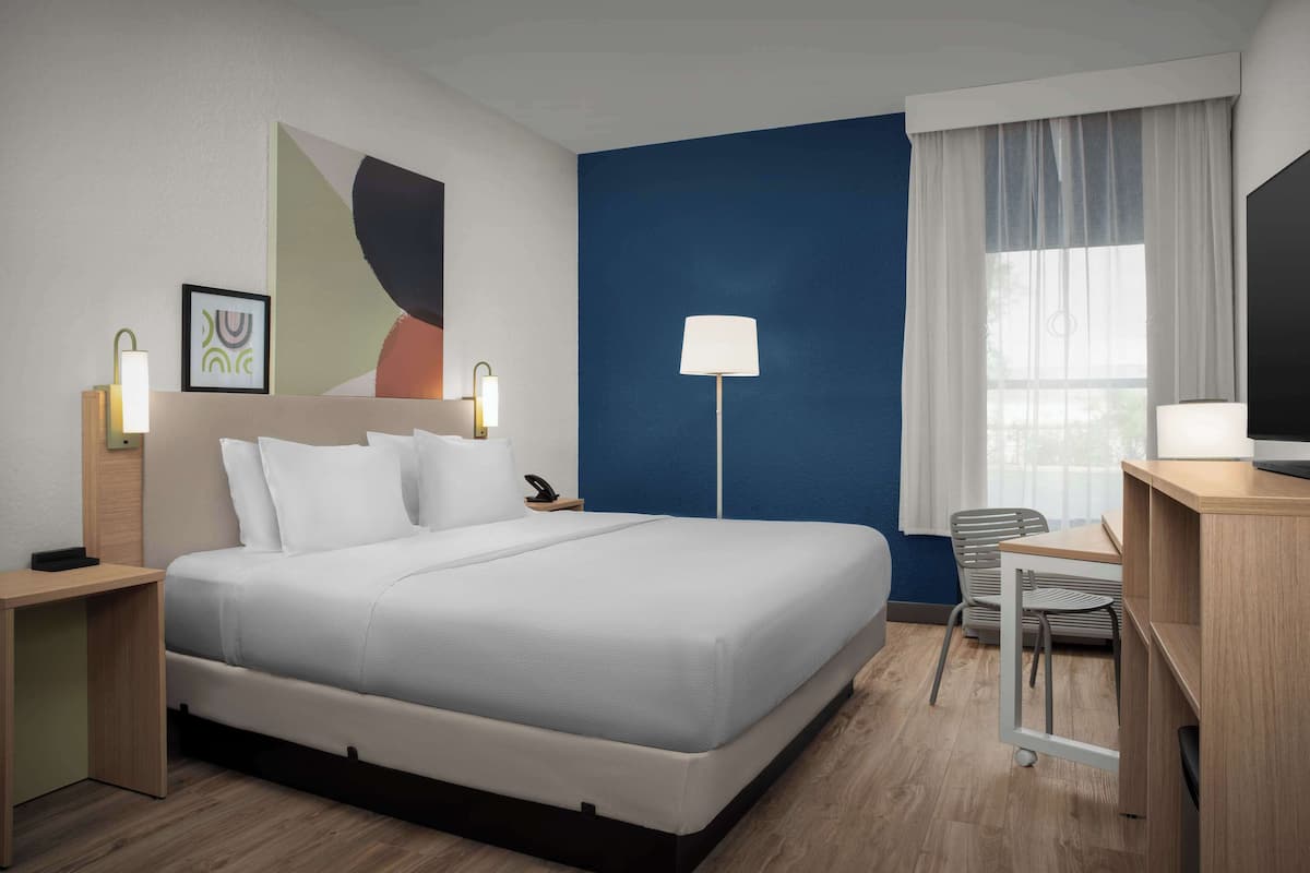 Una habitación de hotel moderna con una cama grande, mesitas de noche, un escritorio y una silla.