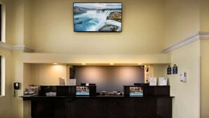 Un área de recepción con un mostrador oscuro, un cuadro de una cascada en la pared y un teléfono a la izquierda.