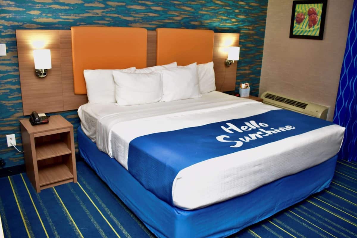 A hotel room with a bed, a nightstand, and a wall-mounted lamp.