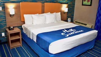 A hotel room with a bed, a nightstand, and a wall-mounted lamp.