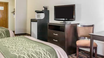 A hotel room with two beds, a desk, a chair, a television, and a coffee machine.
