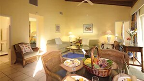 A cozy living room with wicker furniture, a ceiling fan, and a dining area with a table set for a meal. - Bay View Suites Paradise Island (Paradise Island)